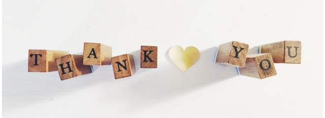 Illustration of wooden blocks spelling out "thank you" with a white paper heart in between the words