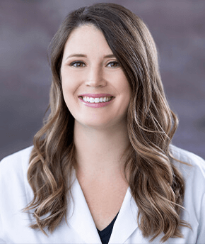 A head shot of a smiling young woman with light brown hair