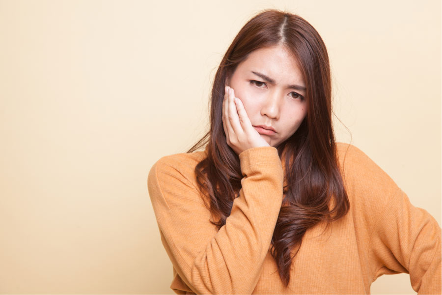 teen holds her jaw and frowns after learning she needs her wisdom teeth removed