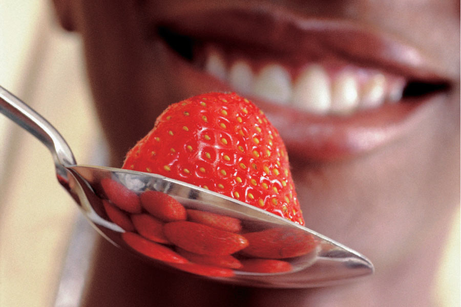 toothy smile getting ready to eat a strawberry off a spoon