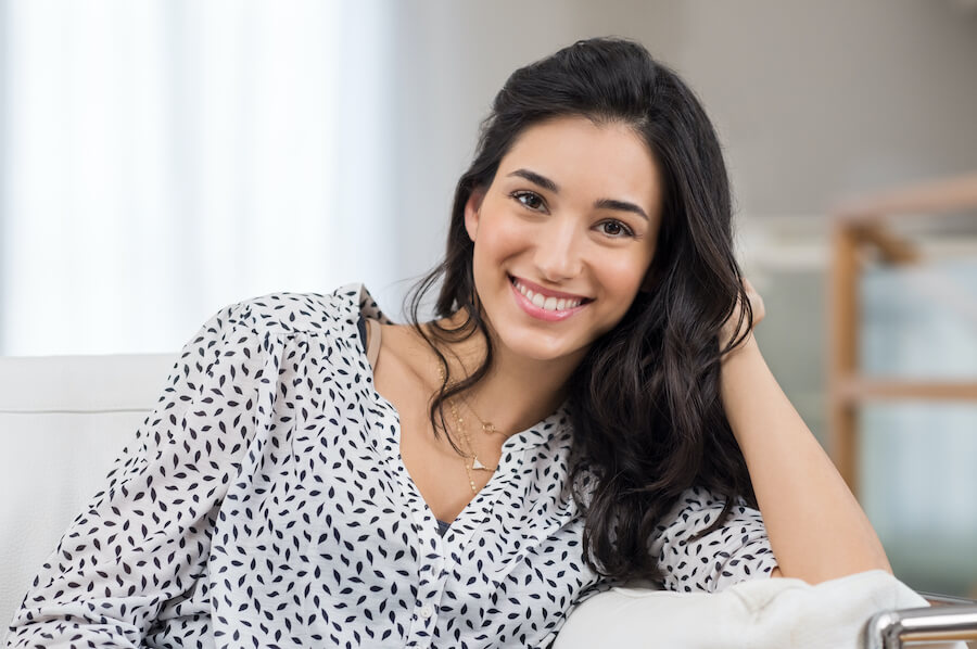 Dark-haired woman in a black and white blouse smiles after receiving BOTOX