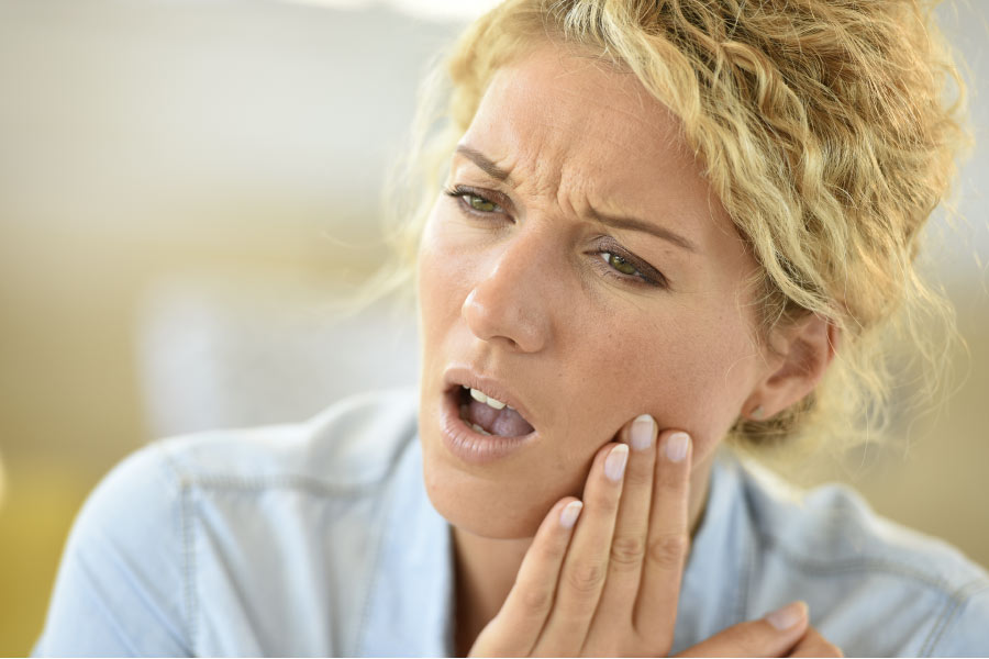 woman holds her jaw in pain with a dental emergency